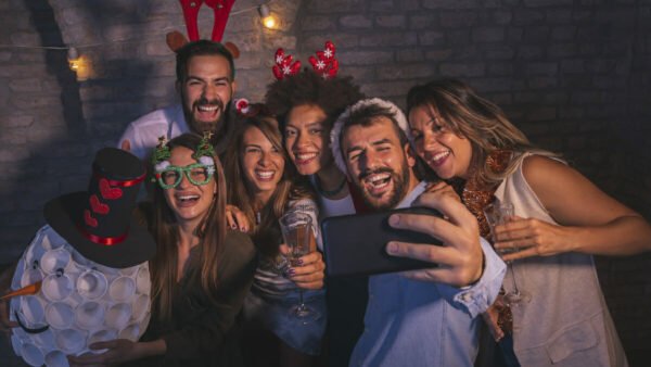 Group of friends having fun at New Year's Eve party, dancing, singing and making crazy faces while taking selfies together
