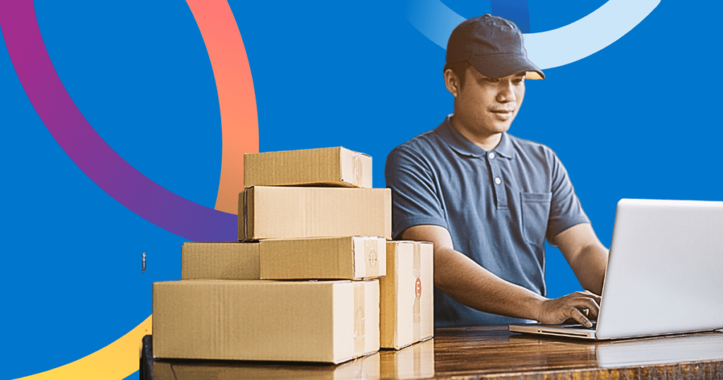 Image of a man working on a laptop with a pile of cardboard boxes next to him on the table